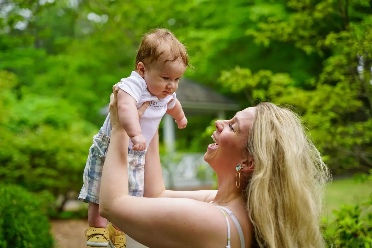 Smiling woman holding baby up outdoors